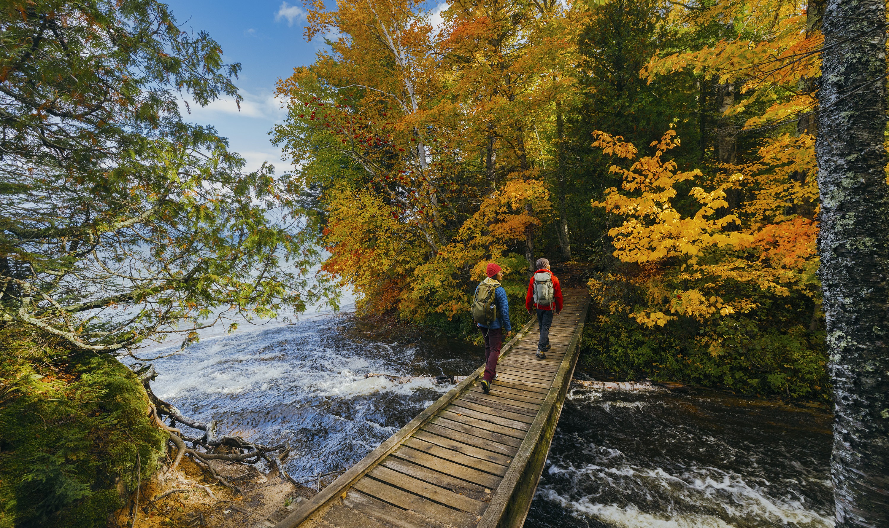 Hiking in Pure Michigan A man and woman hiking across bridge along Lake Superior